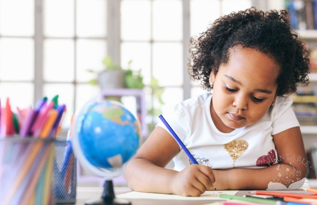 child writing on a worksheet with small globe in forefront